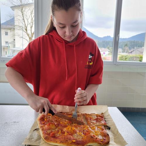 Schülerin beim Aufschneiden der Pizza.